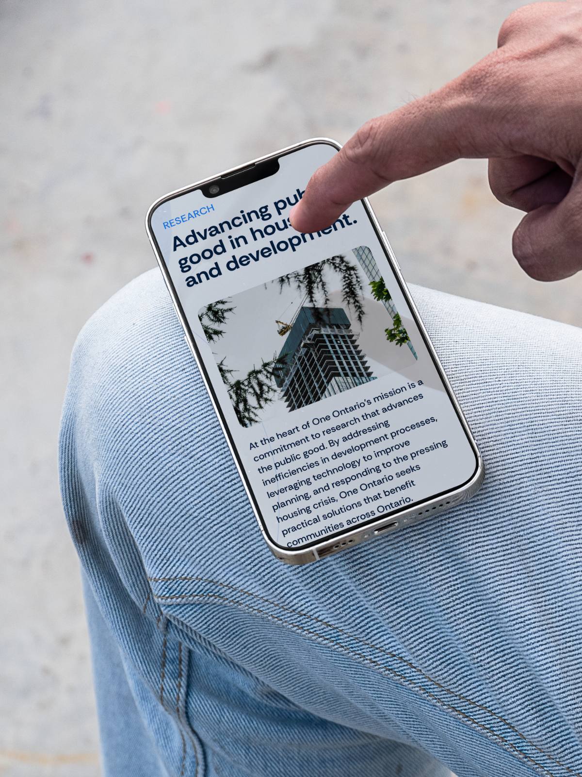 Finger tapping a phone showing the One Ontario research page